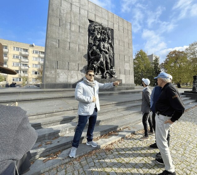 A man pointing at a large sculpture on a building. 1