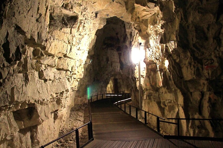 A stone-walled cave with a wooden walkway and railings. 5