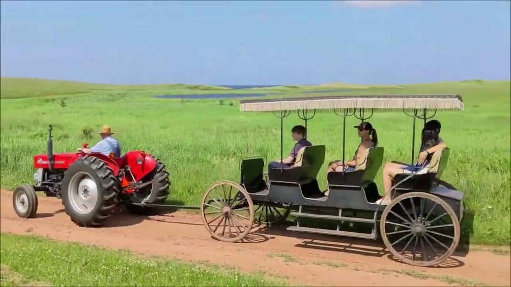 A red tractor pulling a covered cart with passengers. 1