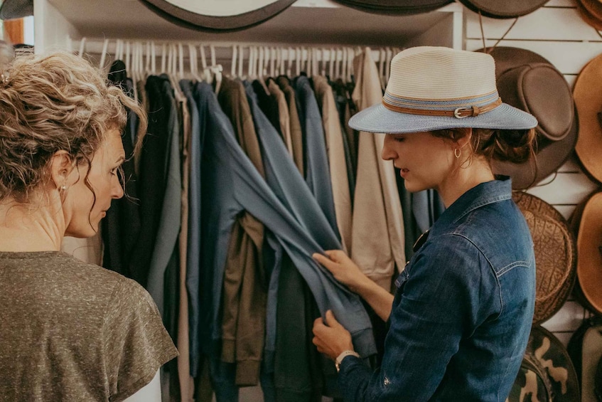 Two people in a clothing store, one holding a jacket. 1