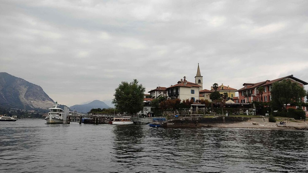 A calm lake with boats, a church, and residential buildings along the shore. 1