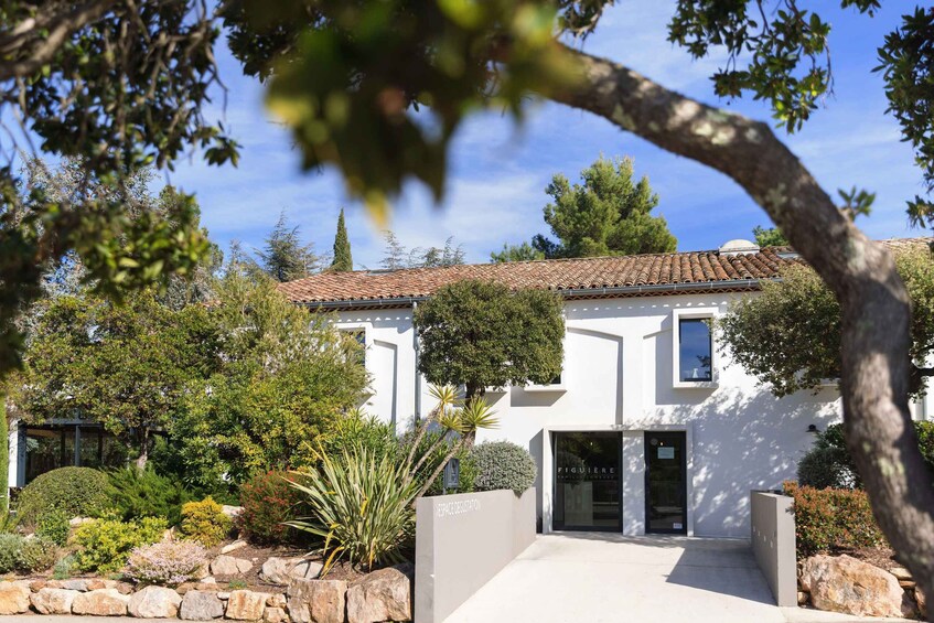 A white building with a tiled roof, surrounded by a landscaped garden with various plants and a stone wall. 3