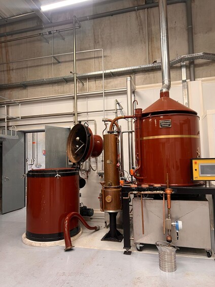A distillery with large copper stills and tanks, pipes, and a control panel. 4
