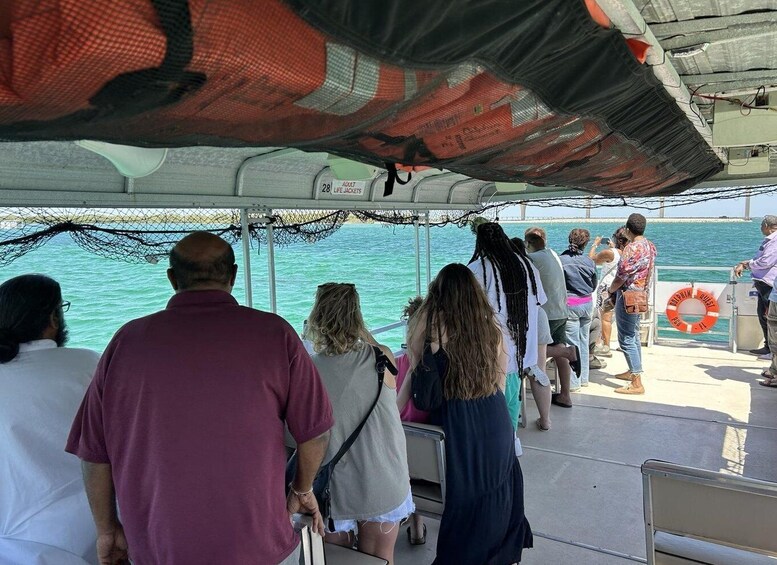 A group of people on a boat, some looking at the water, with a life ring visible. 4