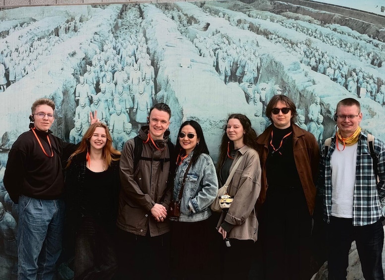 A group of people standing in front of a mural depicting a historical battle scene. 3