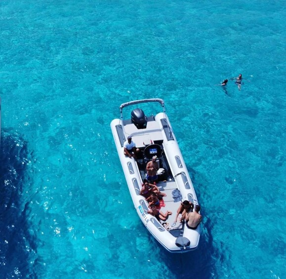 A small inflatable boat with people on it, floating on clear blue water. 5