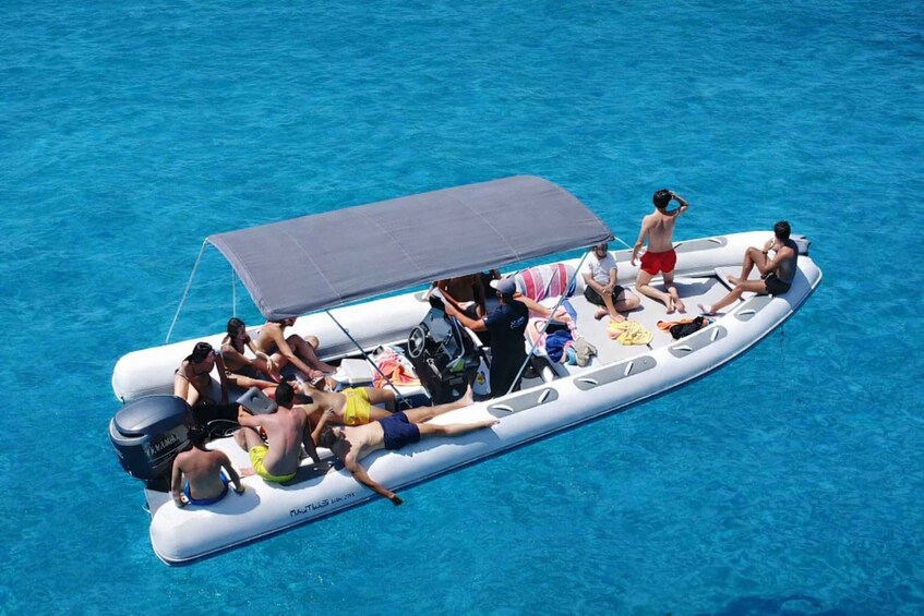 A group of people on a motorized inflatable boat in a clear blue body of water. 3