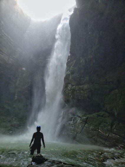 A waterfall in a rocky canyon with a person standing in the water. 3