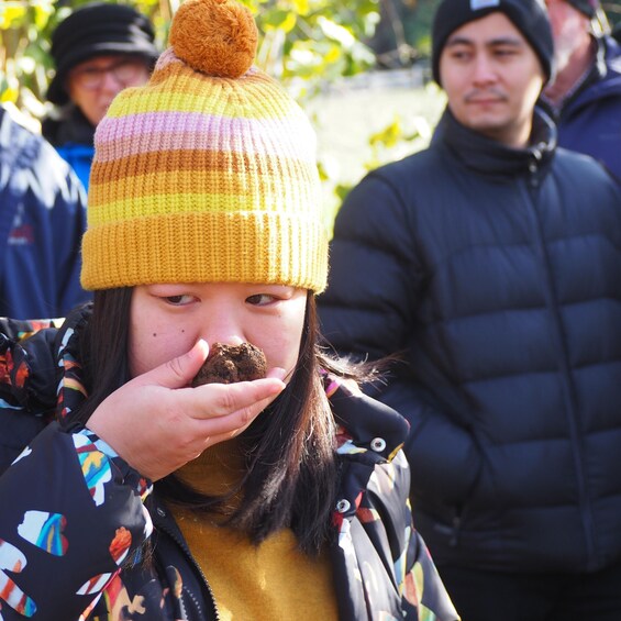 A person wearing a colorful knitted hat with a pom-pom, holding a brown object. 2