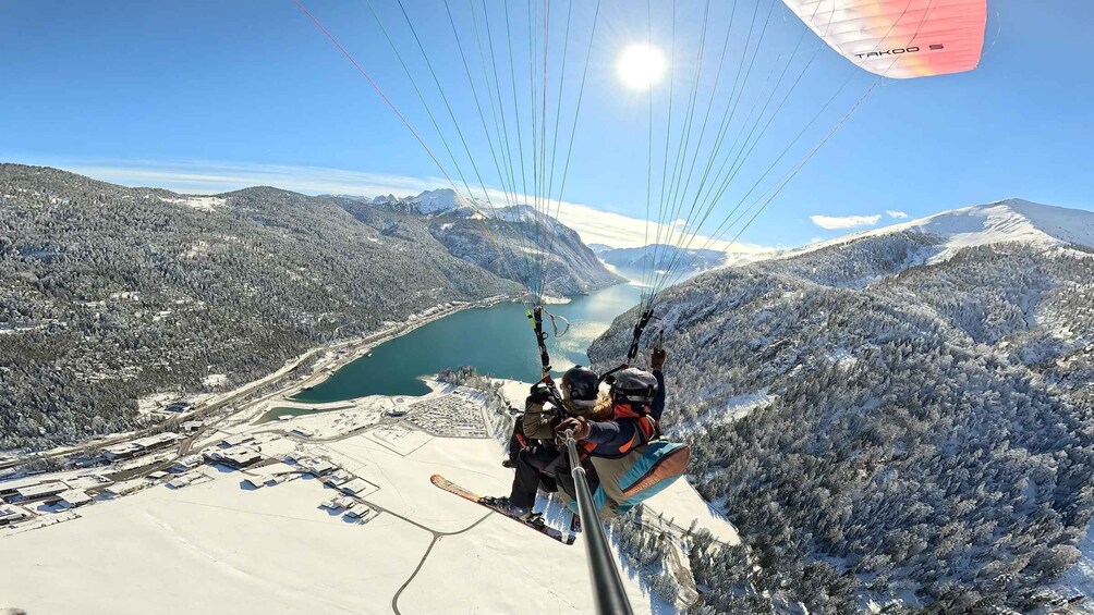 A paragliding scene with a mountainous landscape and a lake below. 2