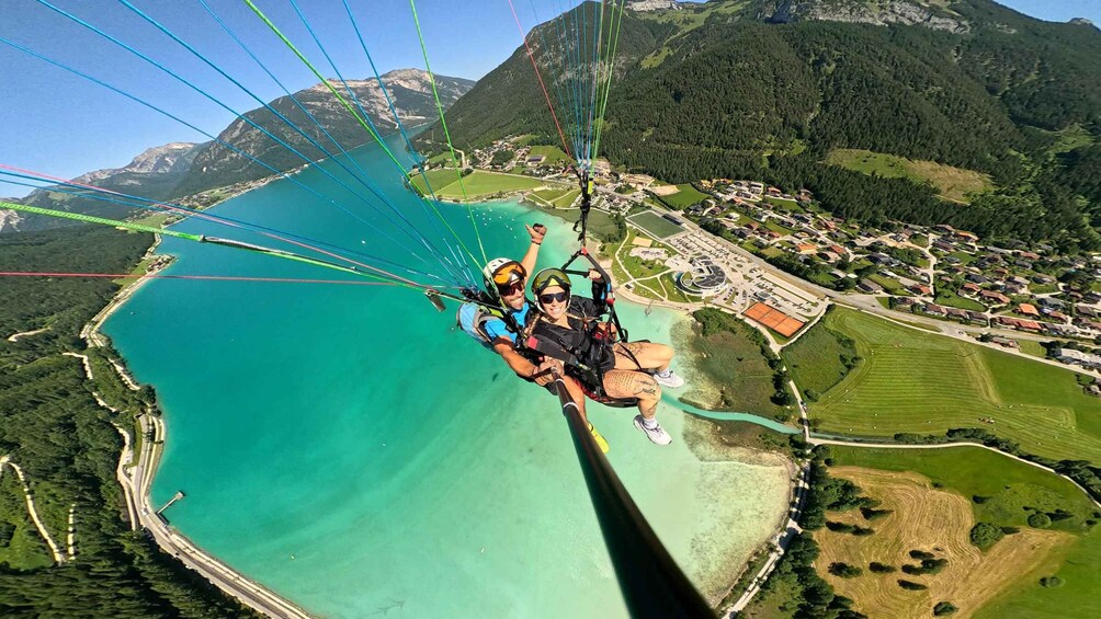 A tandem paragliding flight over a coastal area with mountains in the background. 3