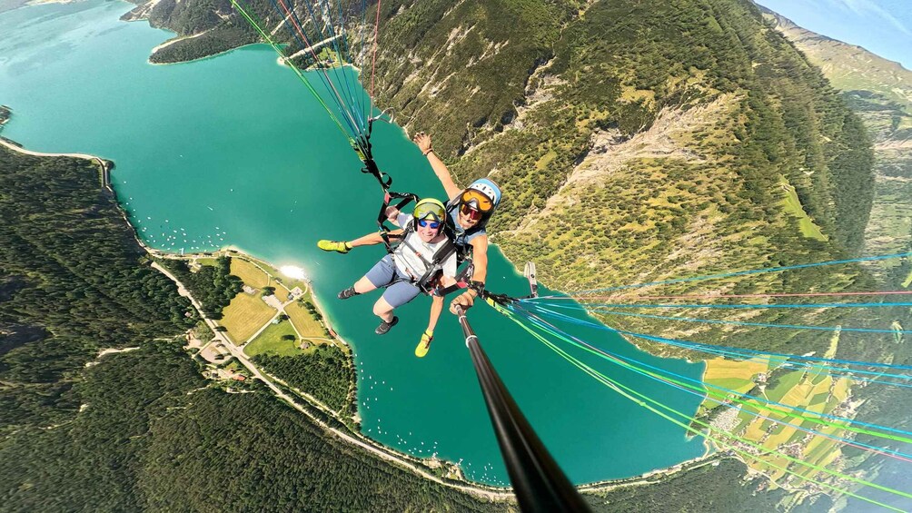 Two people skydiving over a coastal landscape with a lake and mountains. 5