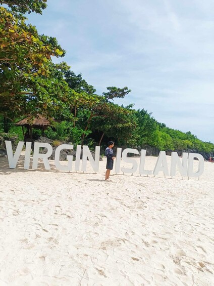 A beach with large white letters spelling 'VIRGIN ISLAND' and a person standing in the sand. 3