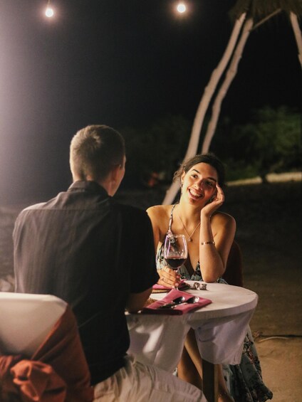 Two people sitting at a round table outdoors at night. 3