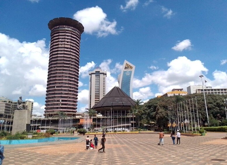 A city square with a tall cylindrical building, a modern skyscraper, and a stadium. 3