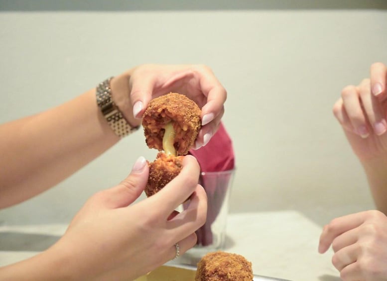 Hands holding a breaded food item with a visible filling. 2