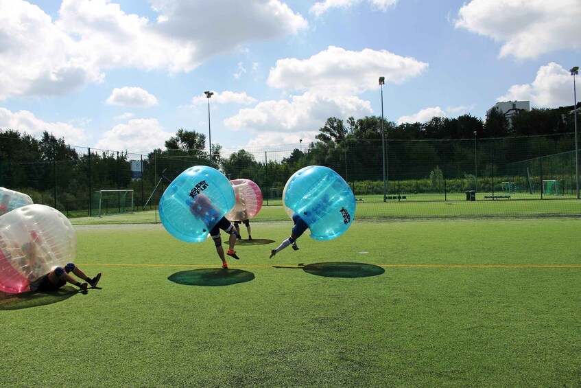People playing with large inflatable balls on a sports field. 5
