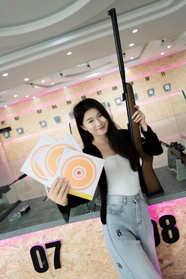 A person holding a rifle and a target with concentric circles. 4