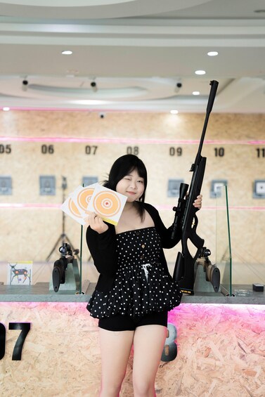 A person holding a rifle and two cards with target designs. 3