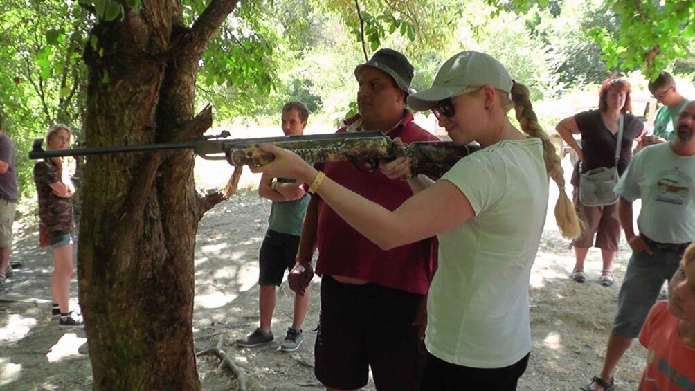 A person aiming a crossbow at a tree. 3