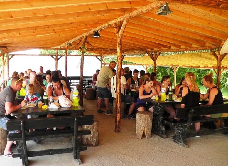 A group of people dining at an outdoor wooden pavilion with tables and benches. 4