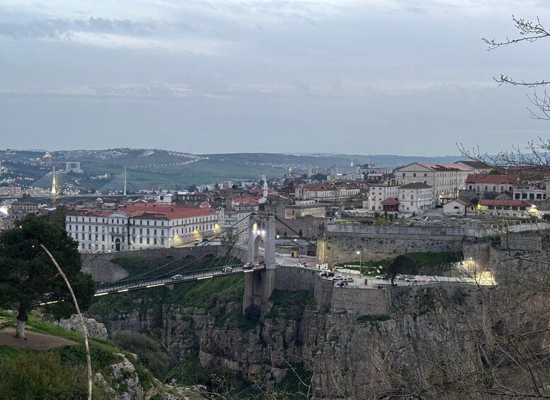 A cityscape with a prominent bridge, historic buildings, and a fortified wall. 2