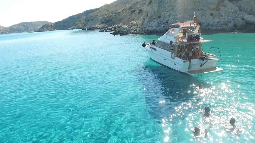 A boat on clear turquoise water with rocky cliffs in the background. 3