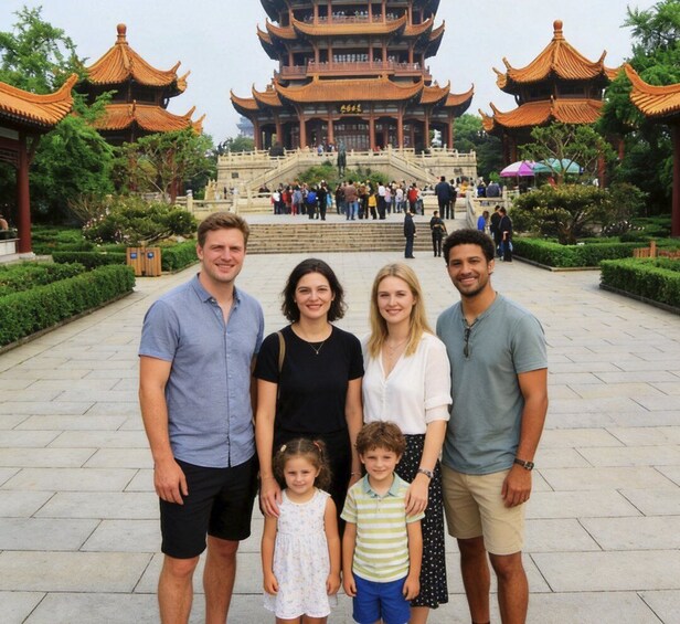 A family in front of a traditional multi-tiered pagoda with a stone staircase leading up to it. 5