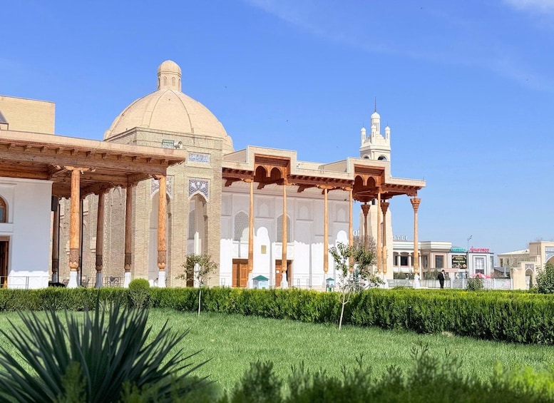 A historic building with a dome and minarets, surrounded by well-maintained hedges and a clear sky. 2