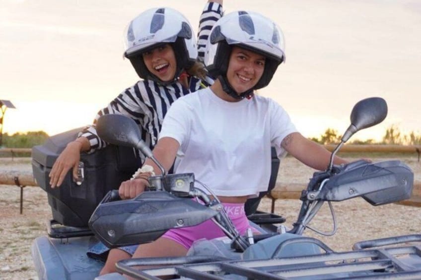 Two people on a scooter, one wearing a helmet, in an outdoor setting with a clear sky. 5