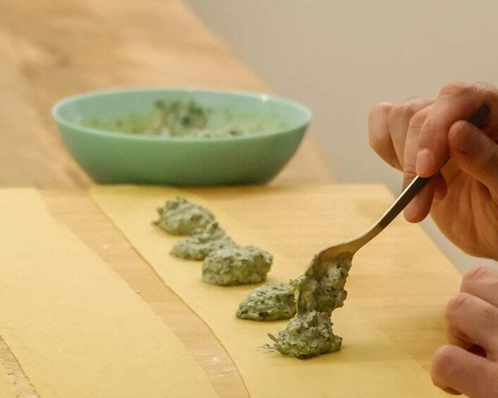 A hand scooping a green substance onto a flat surface. 3