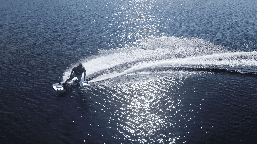 A person jet-skiing on water with a wake. 2