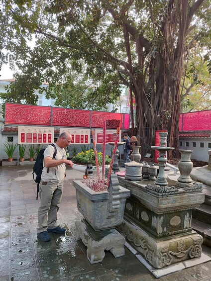 A man performing a ritual at a traditional water fountain with intricate stone carvings. 2