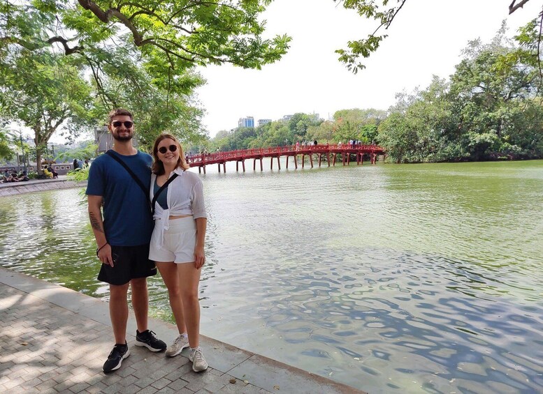 A couple standing by a lake with a red bridge in the background. 4