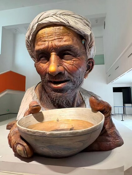 A sculpture of a person holding a bowl. 1