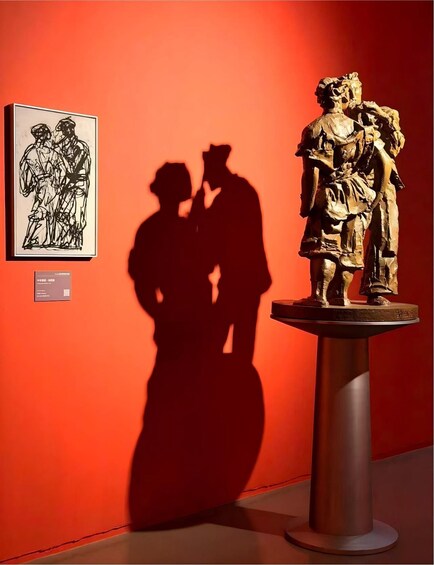 A sculpture of a man and woman in a shadow, with a framed painting of a similar scene on the wall. 4