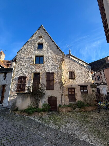 A stone building with a steep roof, wooden shutters, and a cobblestone street. 3