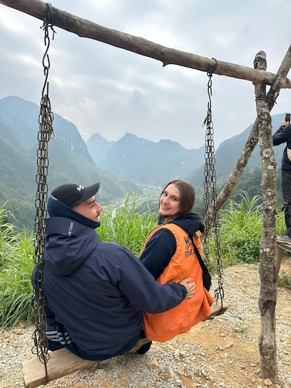 Two people on a swing overlooking a mountainous landscape. 2