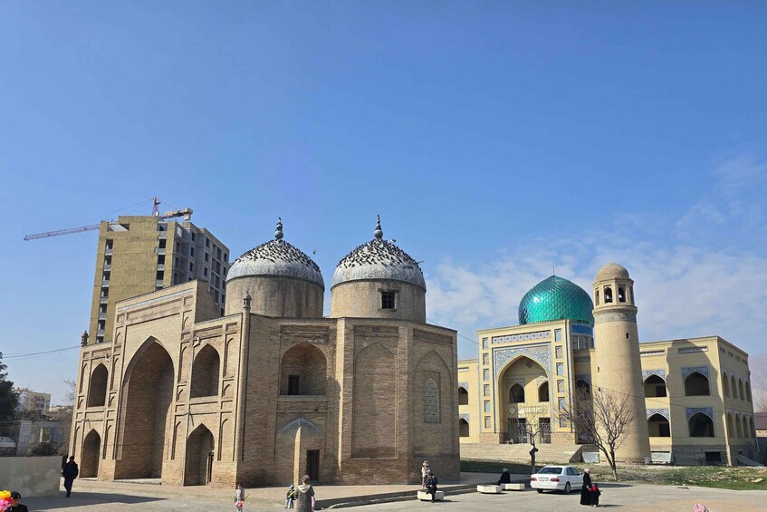 A historic building with domes and a minaret, surrounded by modern structures. 2