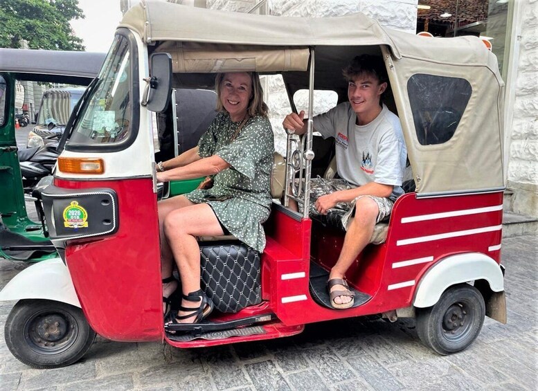 A red and white auto-rickshaw with a beige canopy, a license plate, and a passenger compartment. 3