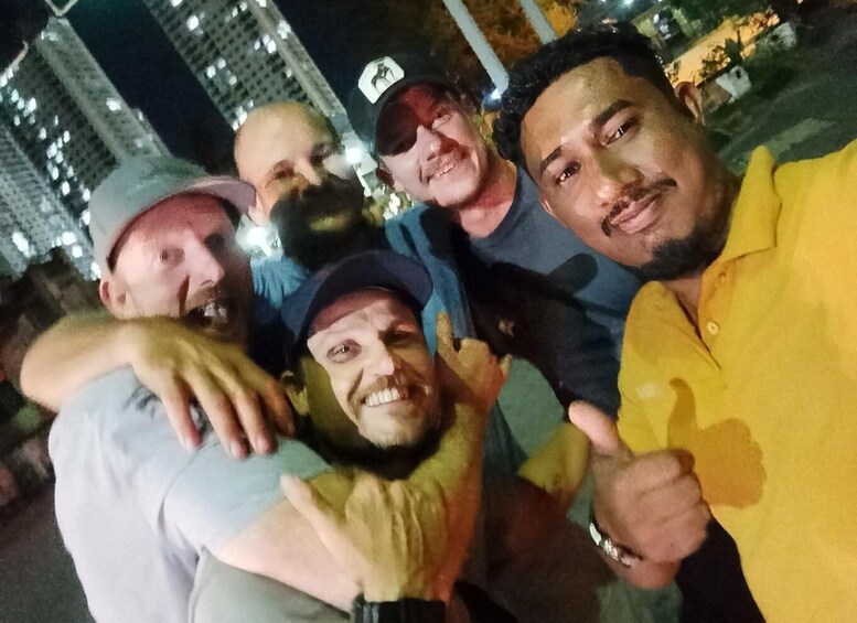 A group of people outdoors at night with buildings in the background. 2