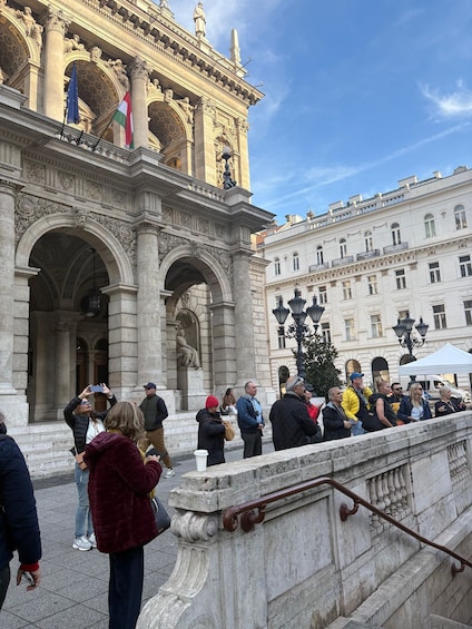 A historic building with ornate architecture and a crowd of people standing in front. 3