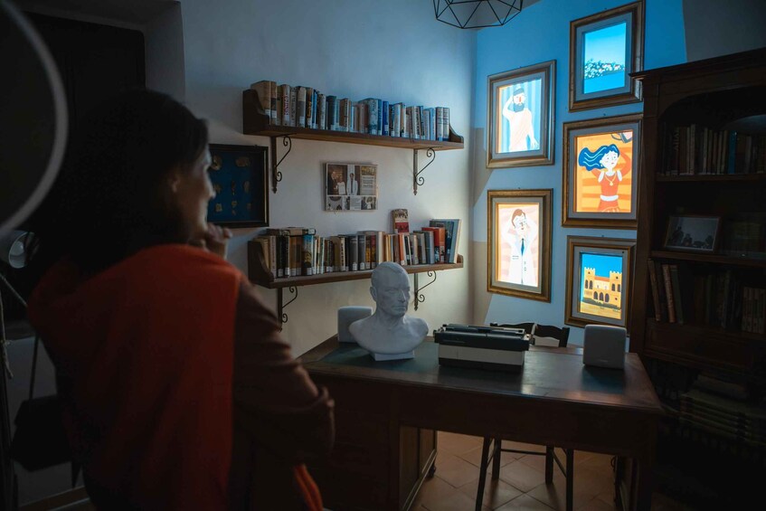 A room with a desk, bookshelves, framed pictures, and a bust sculpture. 4