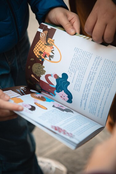 A person holding an open book with illustrations and text. 1