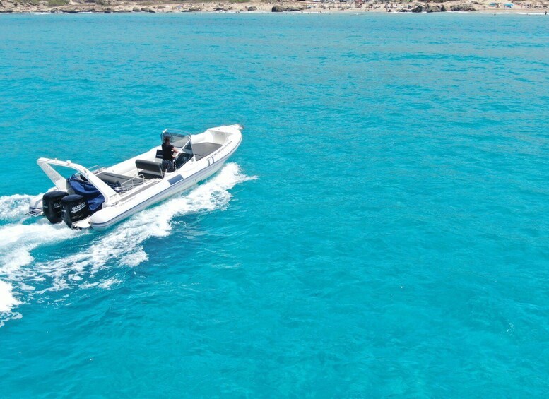 A white motorboat with blue trim and a Suzuki logo on the back, moving through turquoise waters. 1