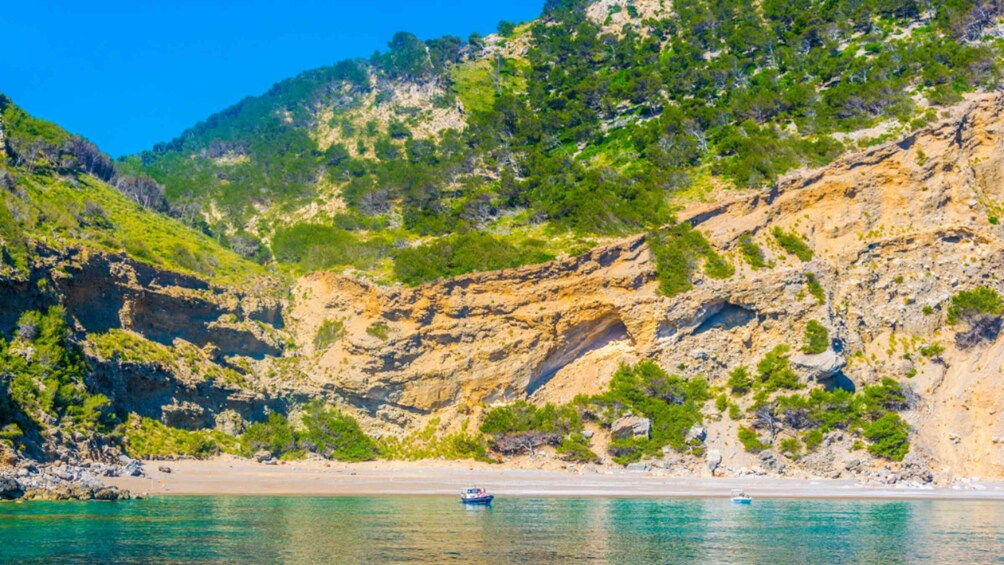 A coastal landscape with cliffs, a beach, and a boat on the water. 3