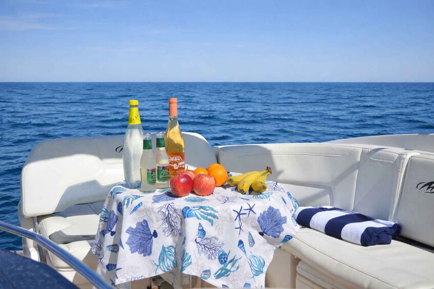 A boat with a table set with fruits, bottles, and a bottle of wine. 4