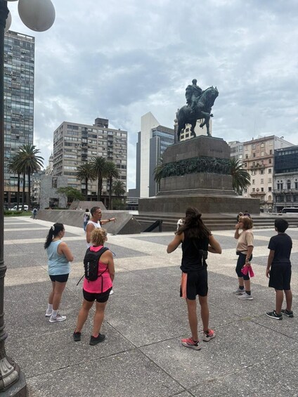 A group of people taking photos in front of a statue of a man on horseback. 3