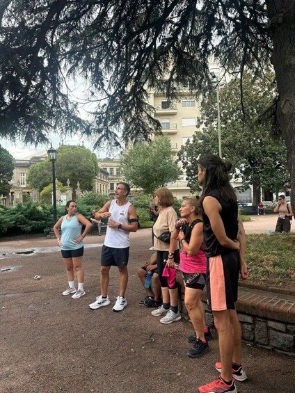 A group of people exercising outdoors in a park with trees and buildings in the background. 2