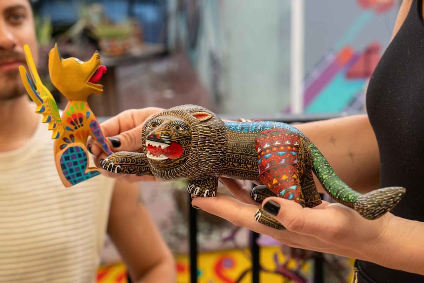 A person holding a colorful, intricately designed toy figure. 1